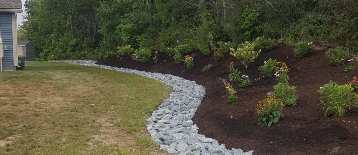 exterior photo of stone drainage ditch with garden landscaping