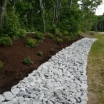exterior photo of stone drainage ditch next to garden landscaping